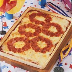 a square pizza sitting on top of a wooden cutting board next to confetti