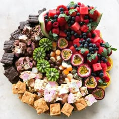 a platter filled with fruit and crackers on top of a table