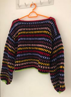 a multicolored sweater hanging on a clothes hanger next to a white wall