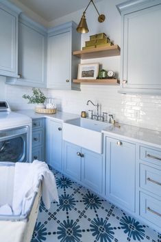 a kitchen with blue and white tile flooring, gold fixtures and open shelving above the sink