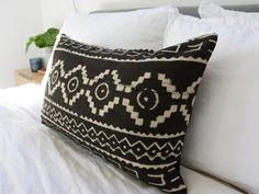 a black and white pillow sitting on top of a bed