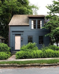 a blue house with trees and bushes around it