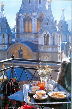 an outdoor table with food and drinks on it in front of a castle like building