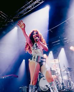 a woman on stage with her arms in the air