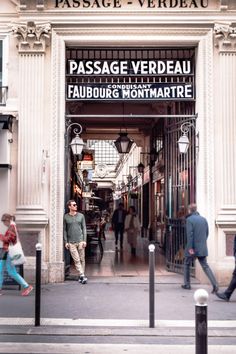 a man is standing in the doorway of a store that has people walking around it