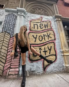 a woman standing in front of a graffiti covered wall with the words new york on it