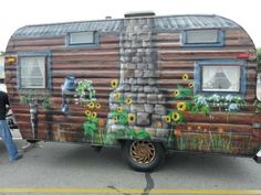 an old trailer with flowers painted on the side