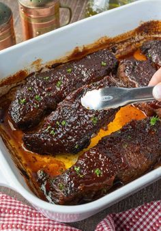 a person is spooning some food out of a casserole dish with meat