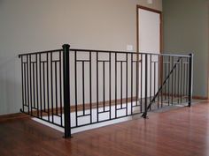 an empty room with wood flooring and black iron railings on the side wall