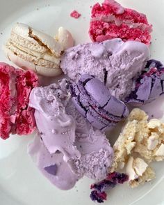 four different colored ice creams on a white plate with pink and purple icing