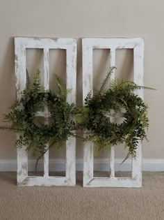 two white wooden frames with wreaths on them