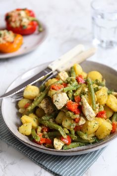 a white plate topped with green beans and potatoes next to a glass of water on a table