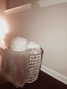 a basket filled with blankets on top of a hard wood floor