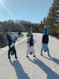 three people standing in the snow with their hands up and one person wearing skis