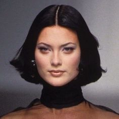 a woman with dark hair wearing a black turtle neck top