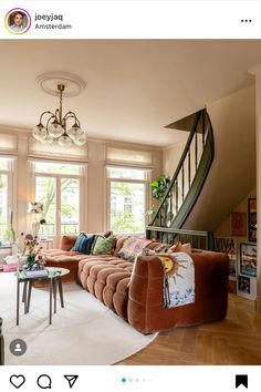 a living room filled with furniture next to a stair case in front of two windows