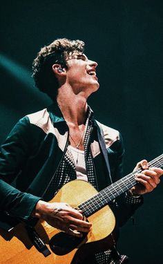 a man holding an acoustic guitar on stage