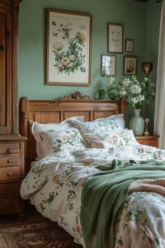 a bed sitting in a bedroom next to a dresser with flowers on it and framed pictures above