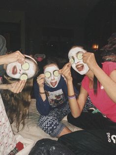 several people with facial masks on and one holding cucumbers in front of their faces