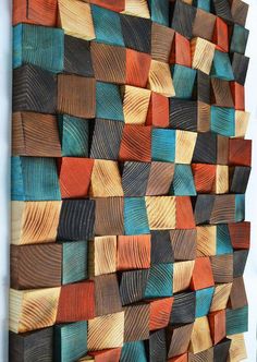 an art piece made out of wood with different colors and shapes on the wall,