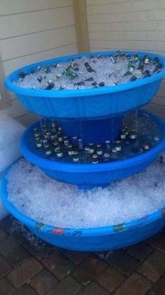 three tiered ice buckets filled with water and soda bottles sitting on top of snow