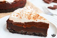 a piece of chocolate cake with white frosting on a plate next to a fork