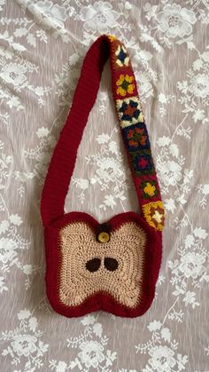 a crocheted red purse with a face on the front and bottom, hanging from a cord