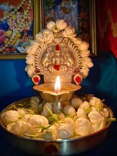 a metal bowl filled with white flowers and a lit candle on top of the bowl