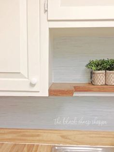 there is a potted plant on the shelf above the sink in this white kitchen