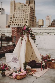 a teepee sitting on top of a sidewalk next to flowers and other things in front of it