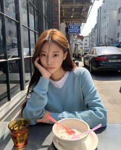 a woman sitting at a table in front of a bowl of food and a drink