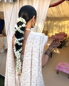 a woman with flowers in her hair wearing a white dress and pearls around her neck