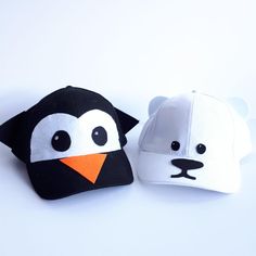 two stuffed animals are sitting next to each other on a white surface, one has a penguin and the other has a polar bear's head