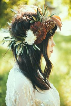 a woman with flowers in her hair wearing a flower crown on her head and looking off into the distance