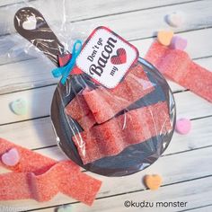 candy candies in a plastic bag on a wooden table with hearts and ribbons around them