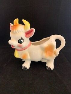 a white and orange cow figurine on a black background