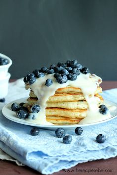 a stack of pancakes covered in blueberries and icing on top of a plate