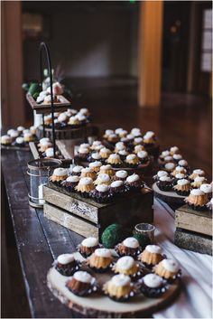 desserts are lined up on wooden trays at a wedding reception, ready to be served