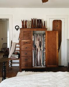 a bedroom with a bed, dresser and closet full of clothing hanging on the wall