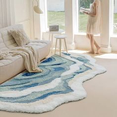 a woman standing next to a couch in a living room with a rug on the floor