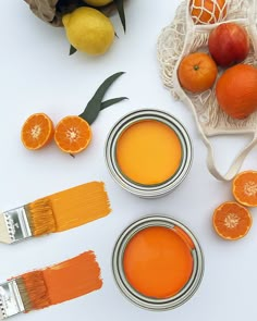 three oranges, two paint brushes and some other items on a white table top