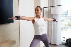 a woman doing exercises with dumbbells in her living room