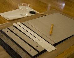 a table topped with notebooks and papers on top of a hard wood floor next to a cup of water