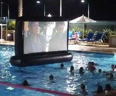 an outdoor movie screen in the middle of a swimming pool