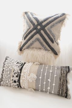 two pillows sitting on top of a white couch next to each other, one with a black and white striped pillow