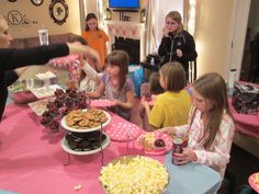 a group of children sitting around a table with food on it