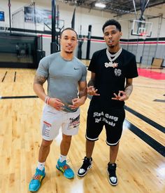 two young men standing on top of a basketball court