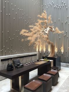 a modern dining table with four stools and a vase on the wall behind it