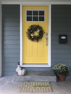 a yellow front door with a wreath on it