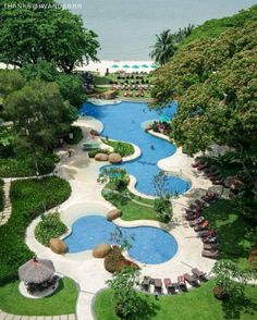 an aerial view of a resort pool surrounded by greenery